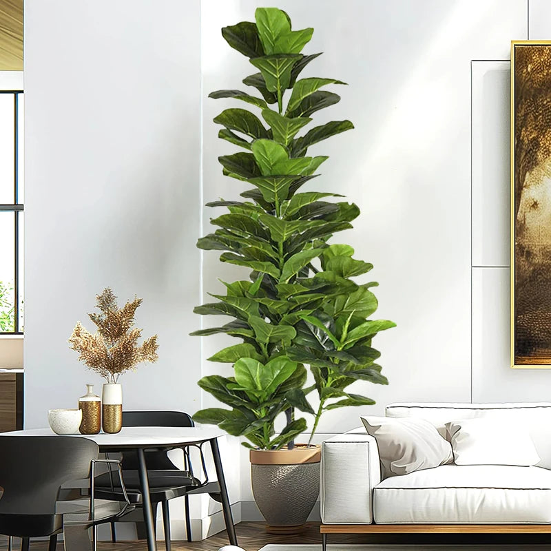 A tall artificial fiddle leaf fig tree in a pot displayed indoors next to a modern white sofa and table.