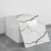A stack of white marble tile stickers with gray veining displayed on a gray floor.