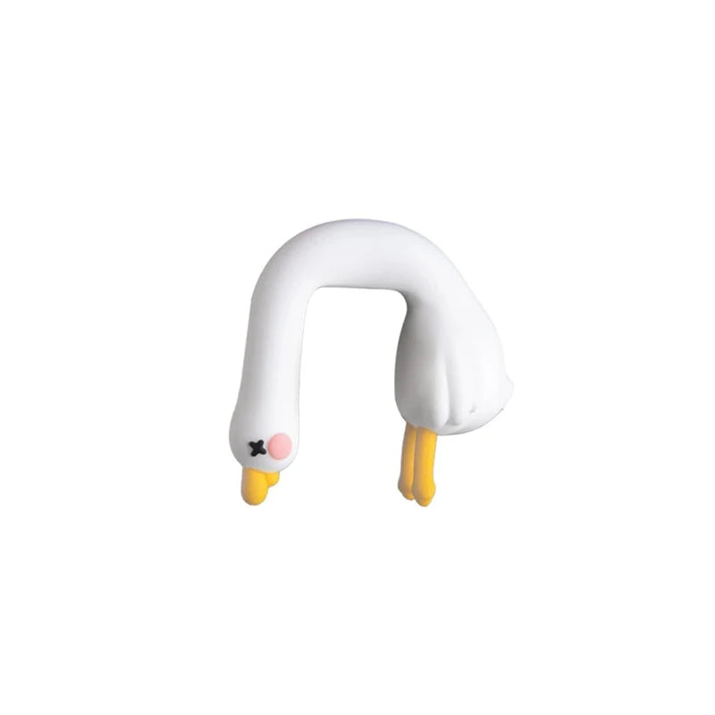 A white resin cartoon duck figurine with yellow beak and pink feet.