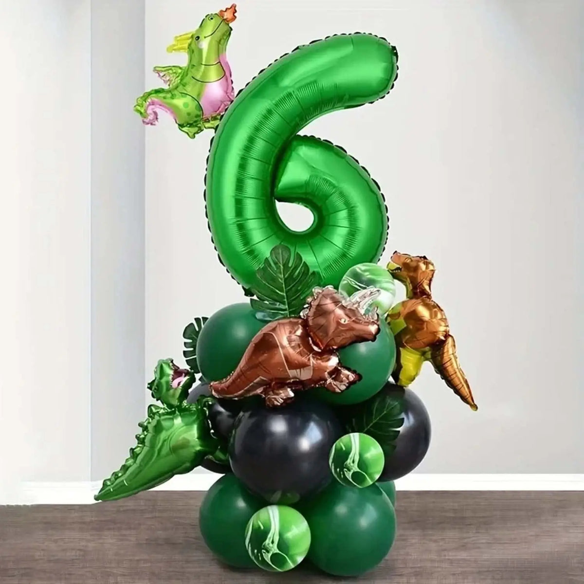 A green foil balloon set shaped like the number six and various dinosaur-themed balloons for a birthday party.