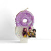 A purple glitter birthday candle shaped like a donut with three character figurines on the base.