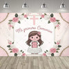 A pink and white First Communion backdrop featuring a girl, a cross, and floral designs.