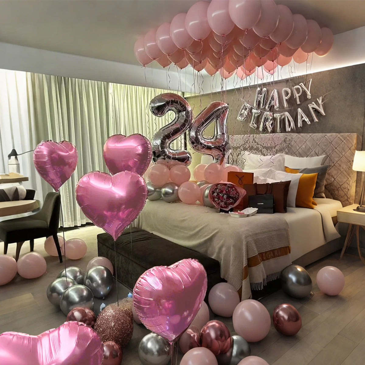 A collection of pink and silver balloons decorating a room for a happy birthday celebration.