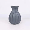 A gray ceramic flower vase with vertical ribbed texture and a flared rim.