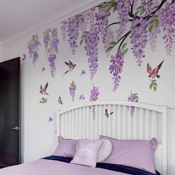 A bedroom wall decorated with watercolor wisteria tree decals featuring purple flowers, birds, and butterflies.