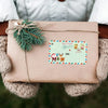 A brown gift box tied with twine and a green sprig, featuring Christmas-themed tags.