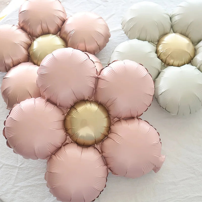 A set of five matte foil flower balloons in pink and gold colors arranged on a white surface.