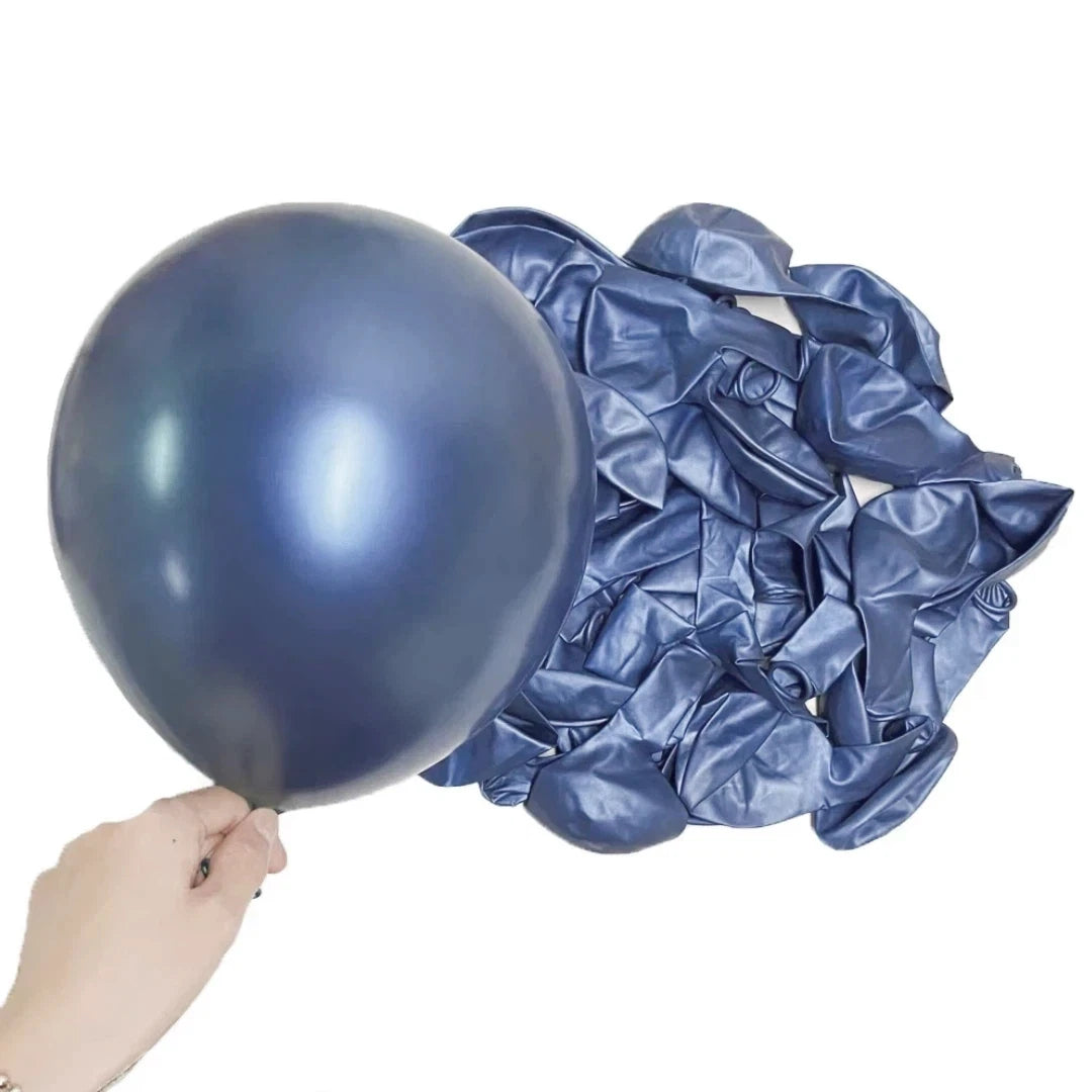 A dark blue metallic latex balloon is being held, next to a pile of crumpled dark blue metallic latex balloons.