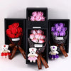 A gift box containing a rose bouquet and a plush bear, with various shades of pink and purple roses.