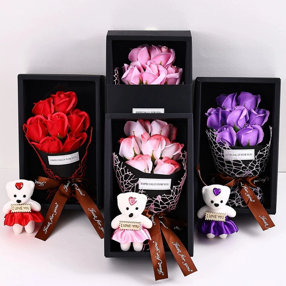 A gift box containing a rose bouquet and a plush bear, with various shades of pink and purple roses.