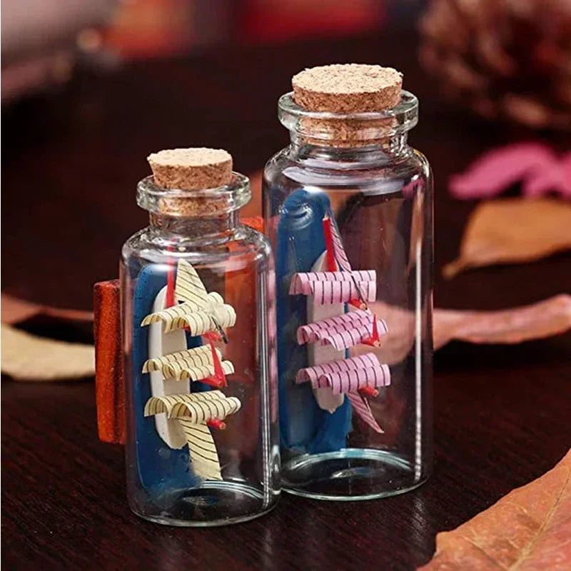 Two glass bottles with cork stoppers containing colorful craft materials like feathers and wood pieces.