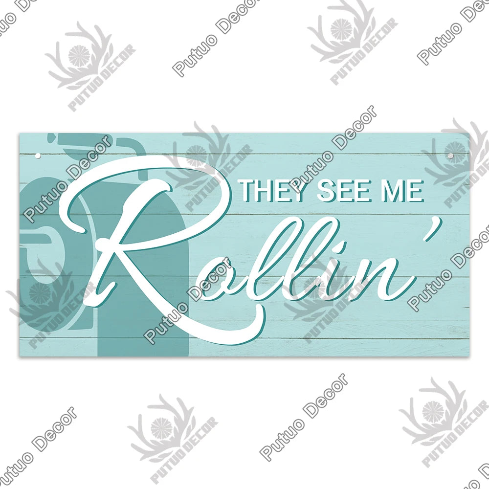 A rustic wooden sign with white script text that reads They See Me Rollin