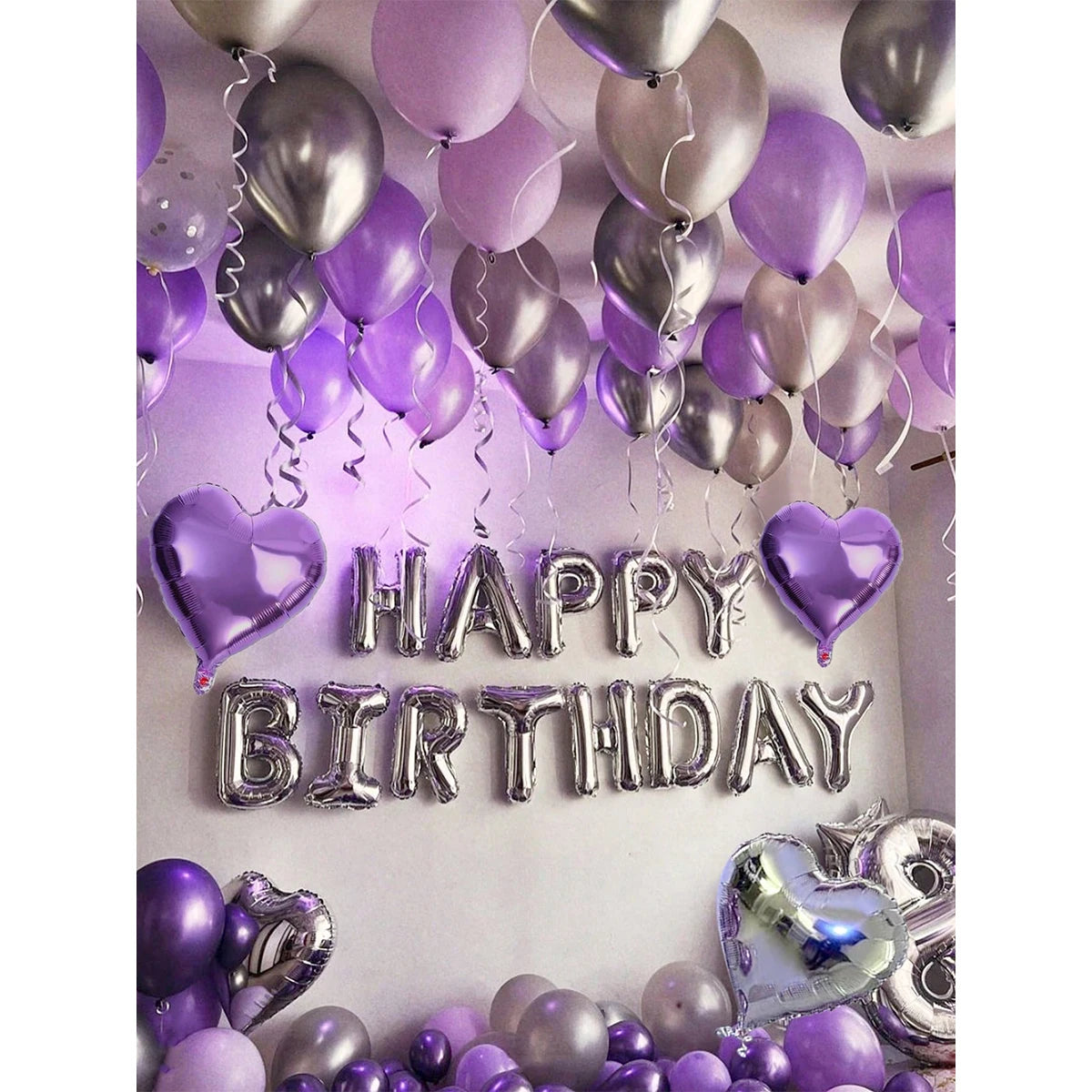 A display of purple and silver metallic balloons and heart-shaped balloons with Happy Birthday lettering.