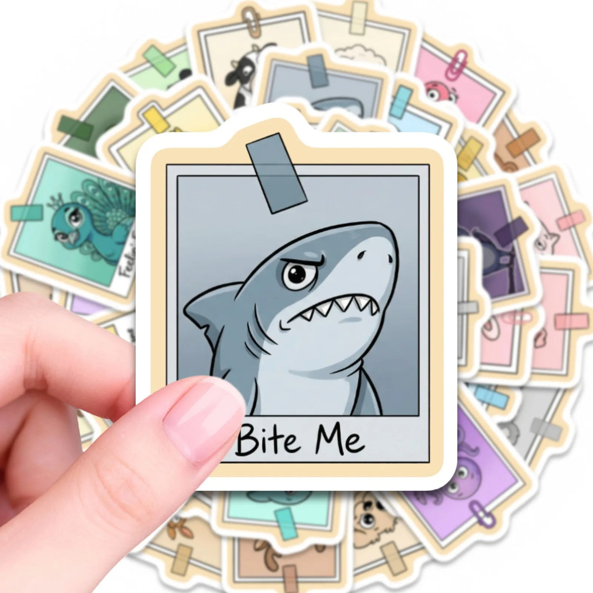 A hand holds a white vinyl sticker featuring a gray shark face with a menacing expression.