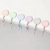 A row of colorful heavy duty purse and bag hooks in pink, mint green, and light blue hanging against a white surface.