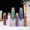 A collection of natural crystal healing stones in glass bottles featuring various colors like green, pink, purple, and blue.