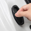 A hand is pressing a black silicone door lock protector onto a white car door surface.