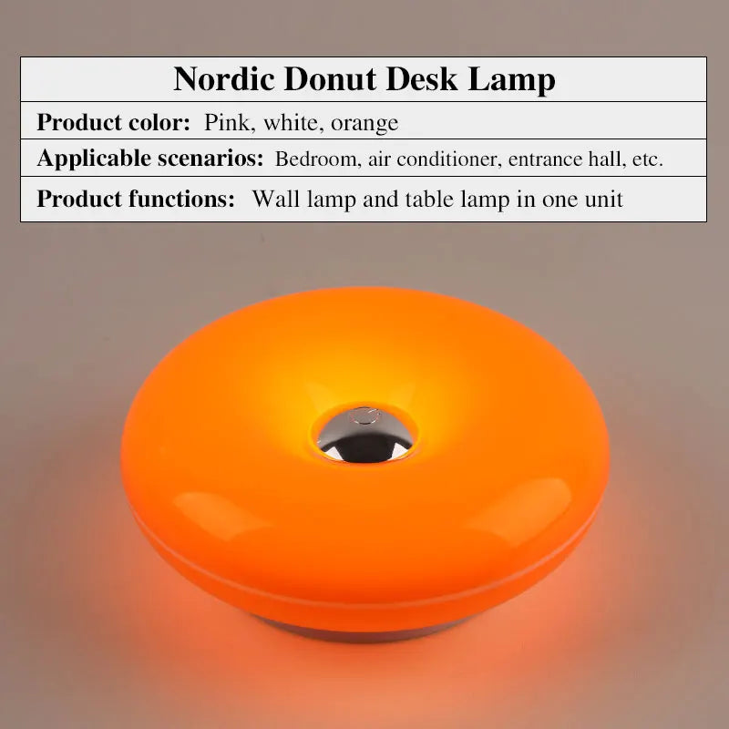 Orangene, donutförmige Schreibtischlampe mit silberner Lichtquelle, die Umgebung beleuchtet.