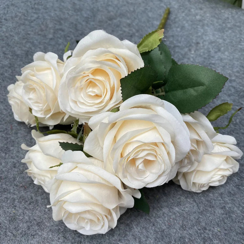 A bouquet of nine creamy white silk roses used for weddings and home decor.
