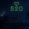 A glowing green heart and the numbers 520 are displayed on a dark wall above a bed.