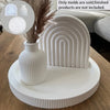 White ribbed silicone mold for crafting, displayed on a wooden surface with dried grasses.