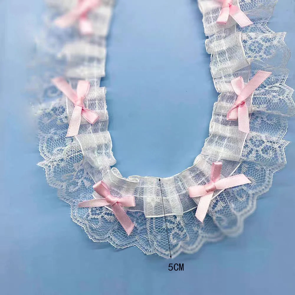 White lace trim with pink bows forming a delicate ruffle collar for a necklace.