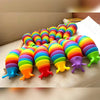 A colorful, flexible 3D articulated fidget slug toy arranged in a rainbow pattern on a white surface.