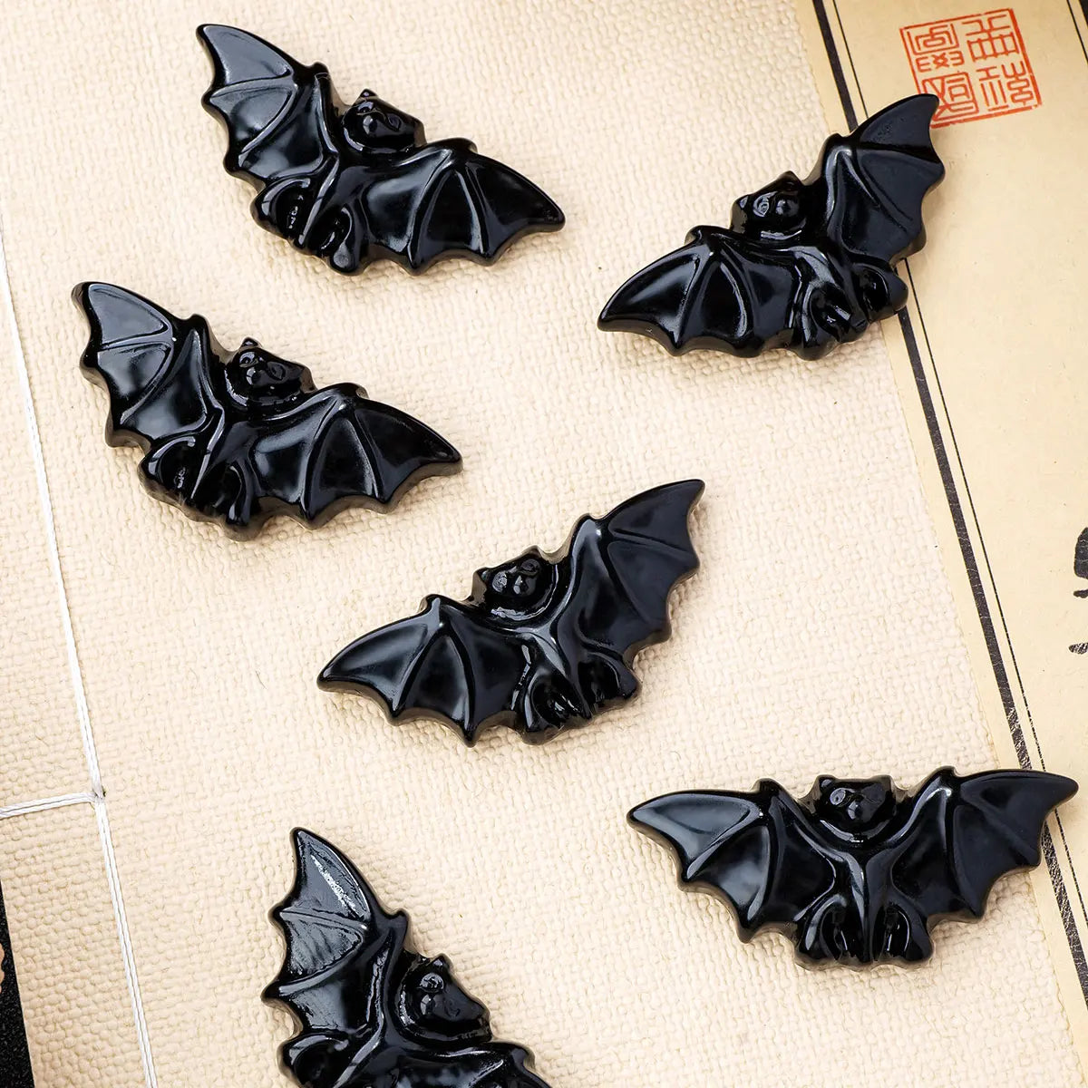 A collection of black hand-carved obsidian bat figurines displayed on a light background.