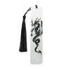 A silver metal dragon design on a white bookmark with a black tassel.