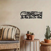 Black Islamic calligraphy art featuring the phrase JacAllah Bless Our Home mounted on a light wall.