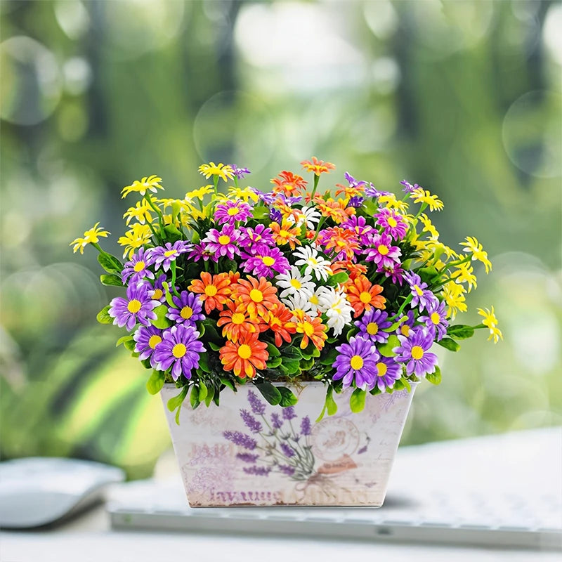 A vibrant bouquet of silk daisies in purple, orange, yellow, and white flowers displayed in a light pink pot.