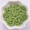 A bowl filled with small, green 3D resin flower gems with yellow centers for crafts and DIY projects