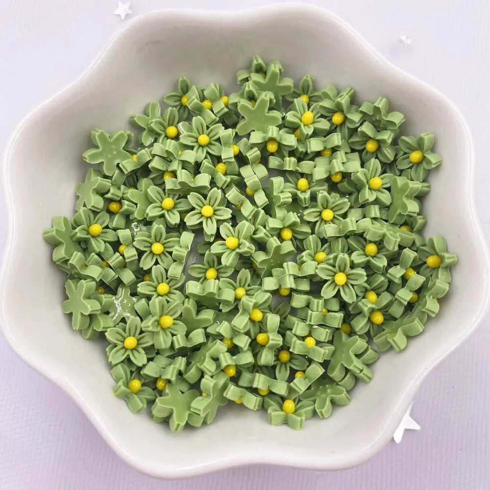 A bowl filled with small, green 3D resin flower gems with yellow centers for crafts and DIY projects