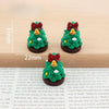 A set of festive Christmas resin decor featuring small green trees with yellow ornaments and red bows.