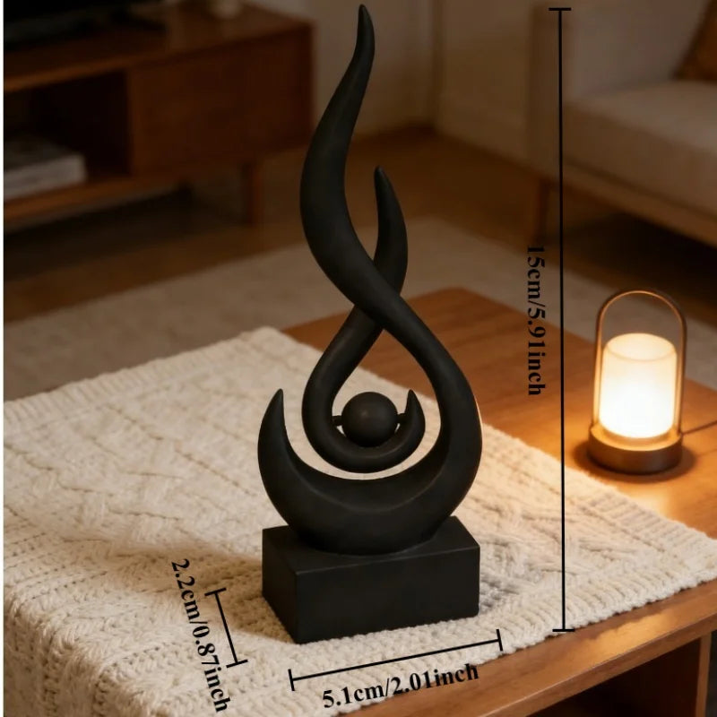 A black, three-dimensional flame sculpture decor resting on a wooden surface and a textured cloth.