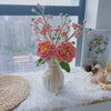A bouquet of handmade crochet flowers in shades of pink and yellow displayed on a white table.