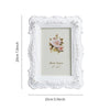 White ornate photo frame with a distressed border and a pink rose floral design inside