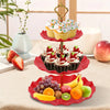 A three-tier plastic dessert stand displaying various cupcakes and fresh fruit.