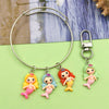 Silver hoop necklace with four resin mermaid princess charms in pink, blue, orange, and green.