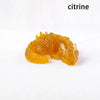 A translucent yellow citrine crystal figurine shaped like a dragon for Feng Shui decor.