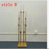 A set of eight gold metal candle holders or candelabra displayed against a white wall.