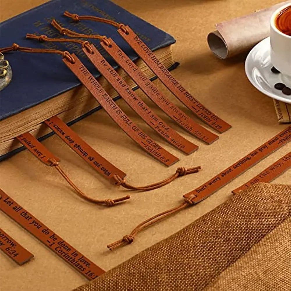 A collection of brown leather bible bookmarks with scripture verses resting on a wooden surface.