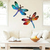 A vibrant blue and green dragonfly wall art sculpture is displayed above a light-colored sofa.