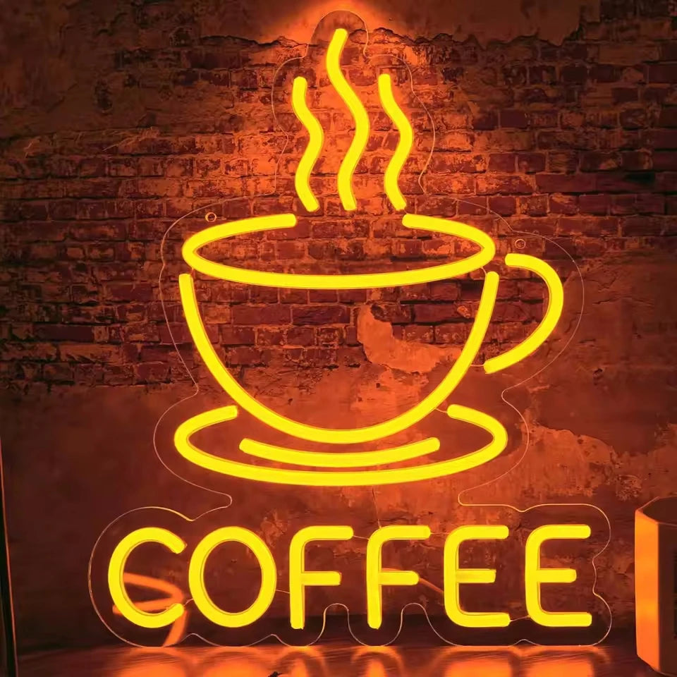 A bright yellow neon sign shaped like a steaming cup of coffee mounted on a brick wall.