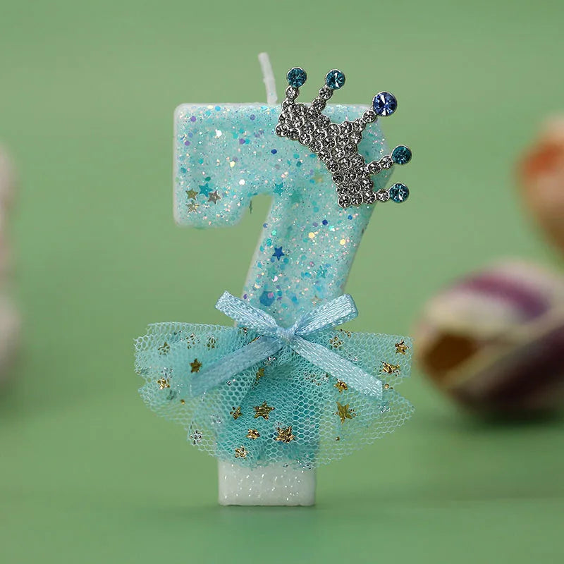 A light blue digital birthday candle shaped like the number 7 decorated with a silver crown and a sheer blue tulle skirt.