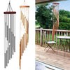 A hanging wind chime set featuring multiple tubes of aluminum with gold and silver bells outdoors on a wooden deck.