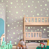A wooden crib with light green star wall decals and a stuffed animal in a nursery setting.