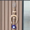 A gold and blue amulet featuring an elephant charm and a blue eye, hanging on a wall.