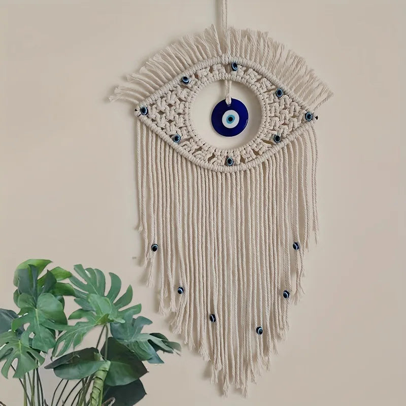 Macrame wall hanging featuring a large eye design with blue and white beads and fringe.