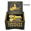 A wooden music box with a gold-colored mechanism and an engraved silhouette of a figure on the lid.